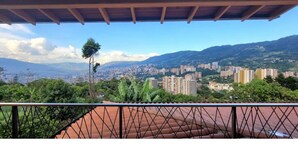 Ein Balkon mit Blick auf eine Stadtlandschaft, einschließlich Wolkenkratzern und Bergen in der Ferne.