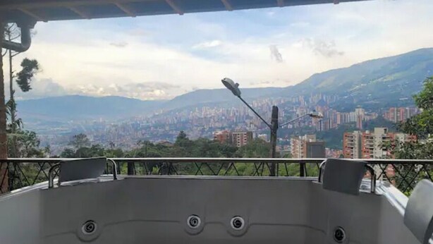 Ein Balkon mit Blick auf die Stadt, einer Whirlwanne und einem Metallgeländer.
