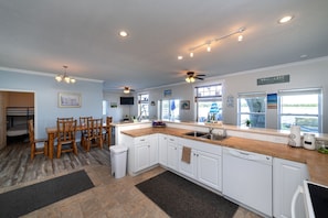 Prepare meals in the spacious kitchen with dishwasher and large sink, and dine at the wooden table with chairs.
