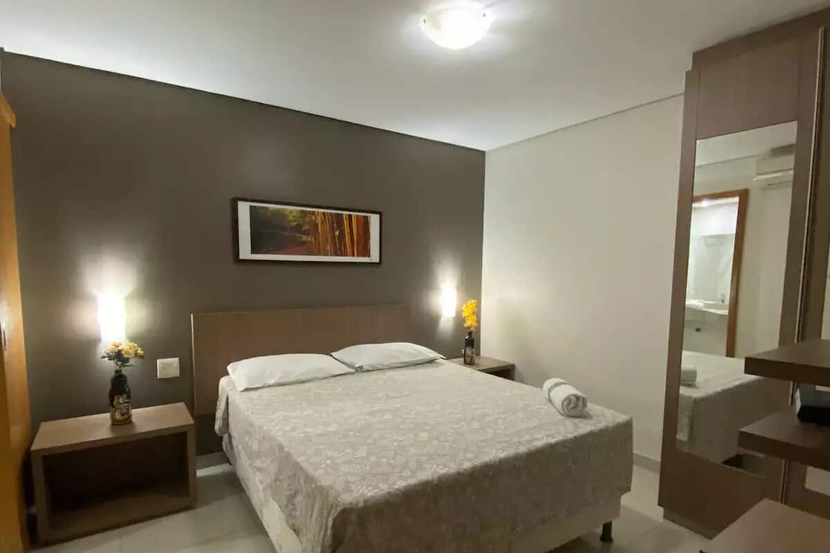 Une chambre à coucher avec un lit, des tables de chevet, une commode, un miroir et un tableau accroché au mur.