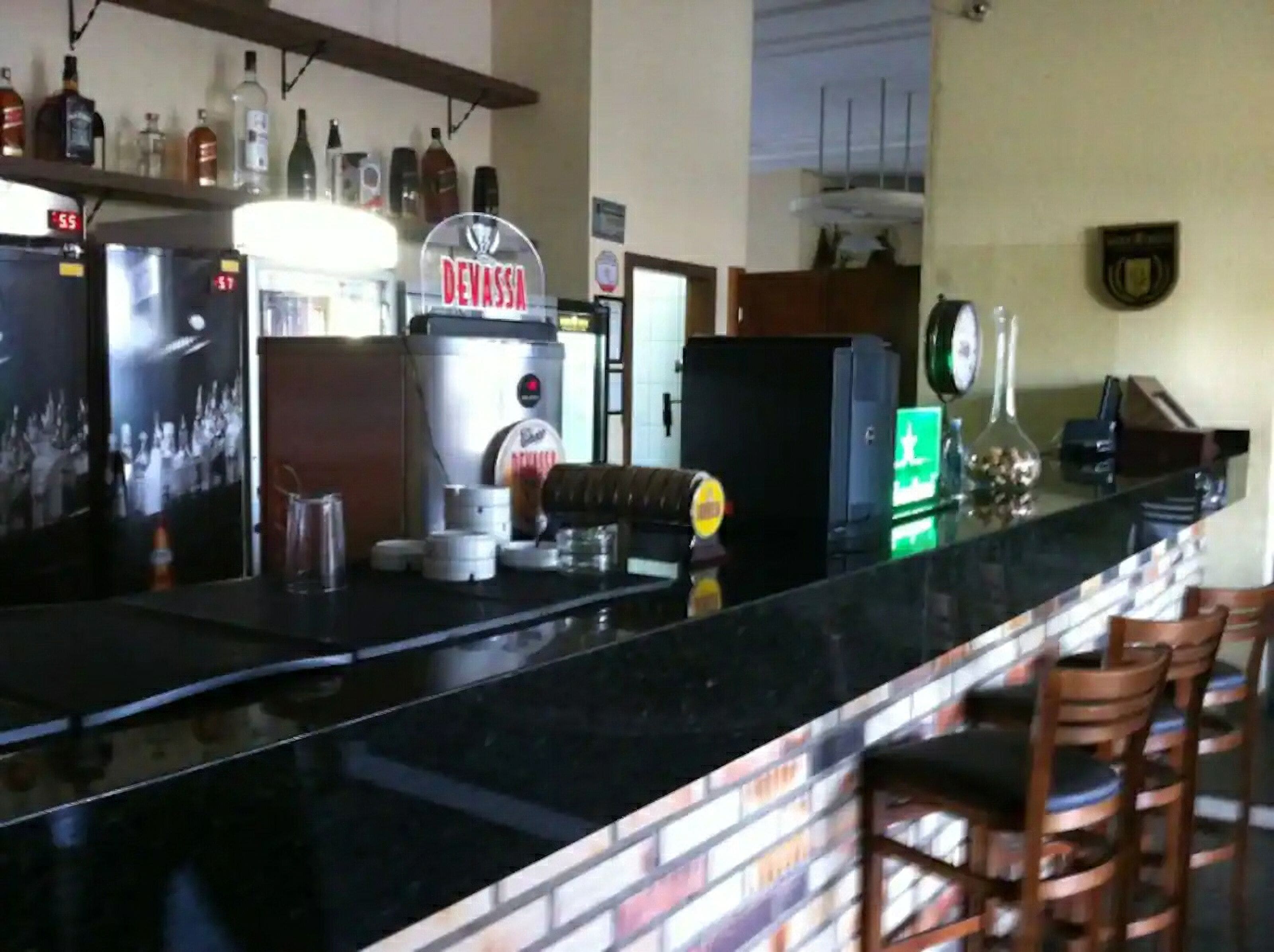 A bar area with a counter, shelves with bottles, a cash register, and a sign that reads "DEVASSA".