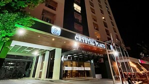 Un grand immeuble avec une enseigne indiquant « CRYSTAL PLACE » à l’entrée.