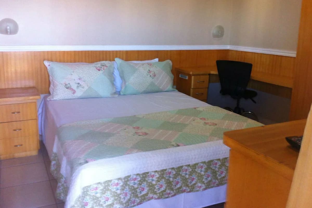 Une chambre à coucher avec un lit, une table de chevet, un bureau et une chaise.