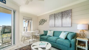 Ein Wohnzimmer mit einem Türkis-farbenen Sofa, einem Couchtisch und einem großen abstrakten Gemälde an der Wand.