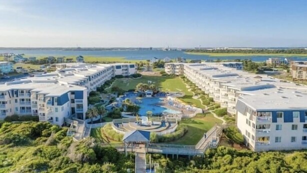 Ein modernes Hotel mit mehreren Gebäuden, einem zentralen Poolbereich und Blick auf das Meer.