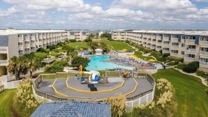 Ein Resort mit zentralem Pool, mehreren Balkonen und gepflegten Rasenflächen.