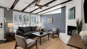 Un salon moderne avec un canapé, des fauteuils, une table basse et une cheminée.