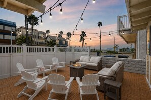 An outdoor patio with white Adirondack chairs, a sofa, and a fire pit. - Ocean just Steps Away! Family and Pet-Friendly (oxnard)