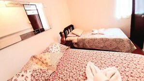 Un dormitorio de hotel pequeño con una cama doble, cabecero de madera y ventana con cortinas.