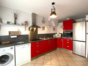 Een koelkast, een oven, een vaatwasser, kookgerei, borden en bestek