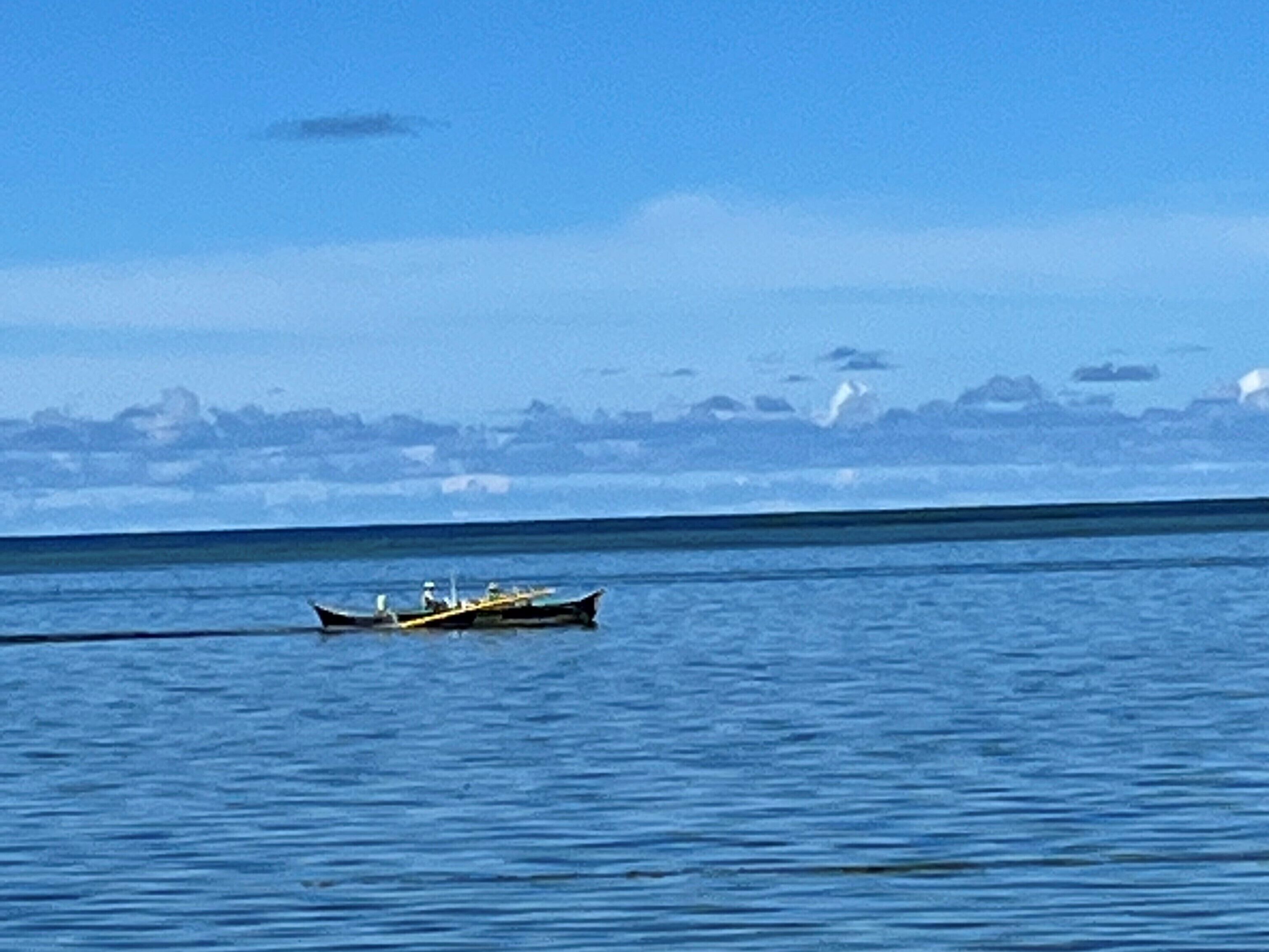 A calm sea with a small boat in the distance.