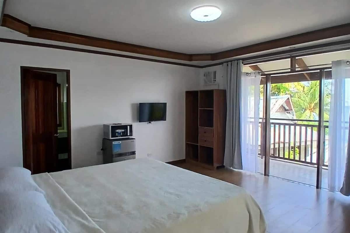 A spacious bedroom with a large bed, a TV, and a wardrobe.