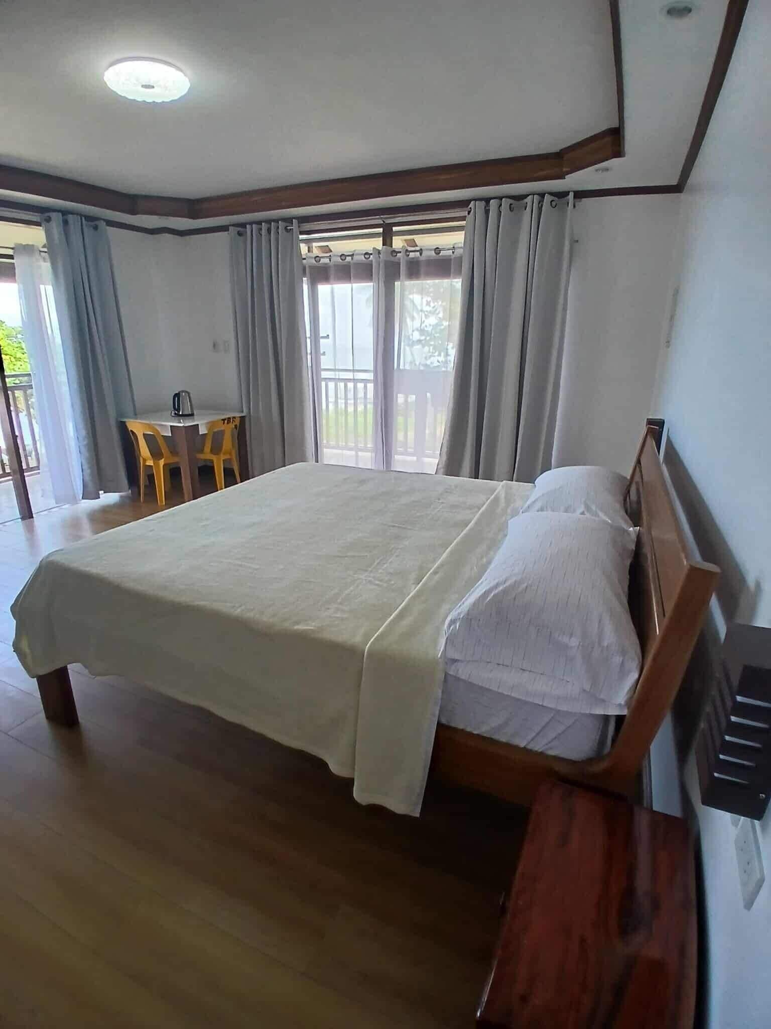 Un dormitorio con una cama grande, cabecera de madera y un escritorio pequeño con sillas.