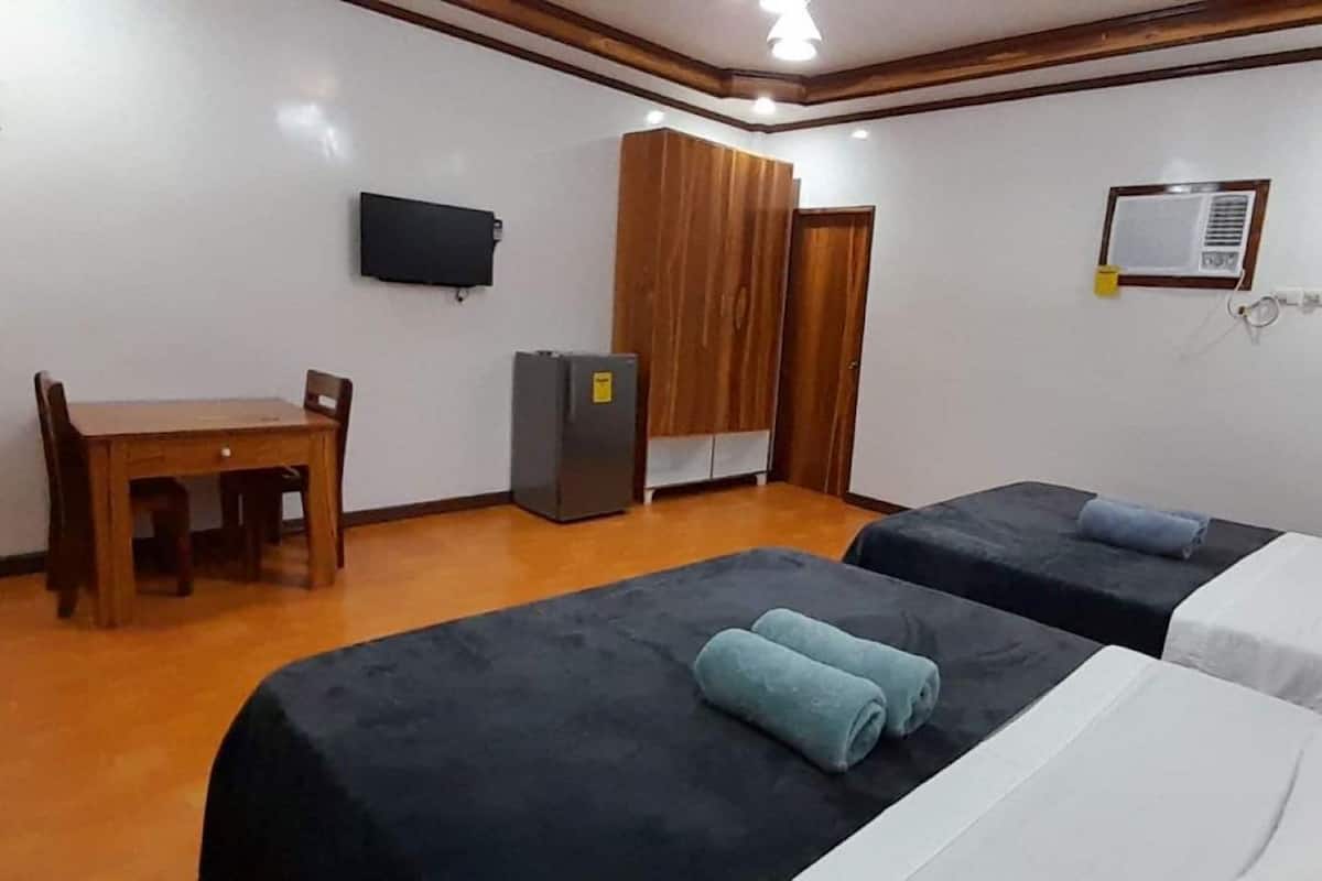 A hotel room with two beds, a desk, a television, and a wardrobe.