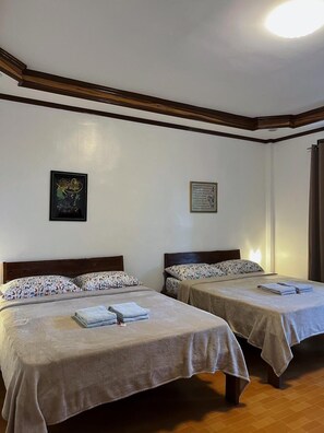 A hotel room with two single beds, each with a floral-patterned bedspread and a folded towel on the bed. - Takbo Beach Resort (General Luna)