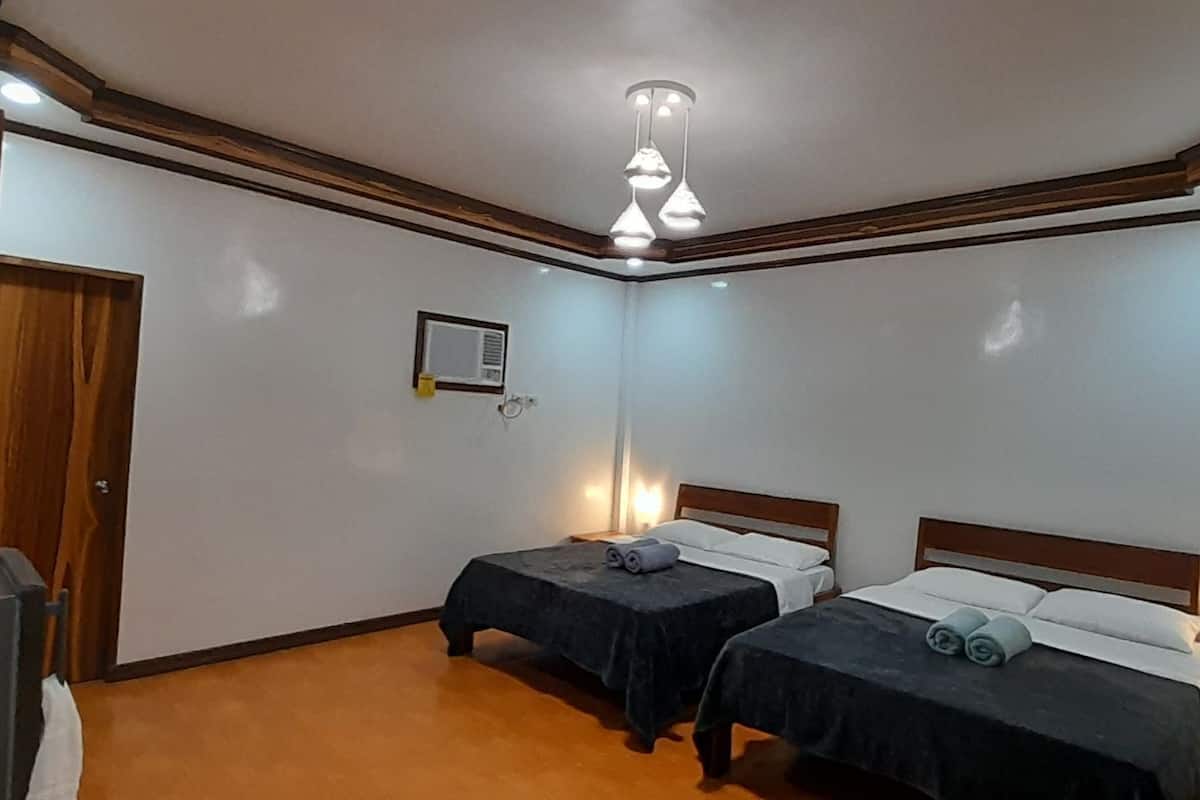 A room with two beds, a desk, and a ceiling light fixture.