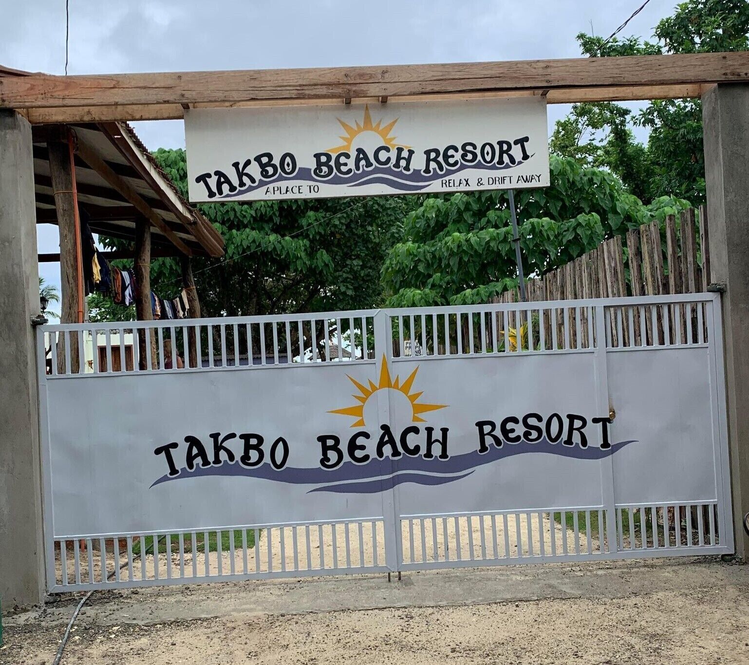 A sign for Takbo Beach Resort with a sun and waves design, indicating a beach theme.