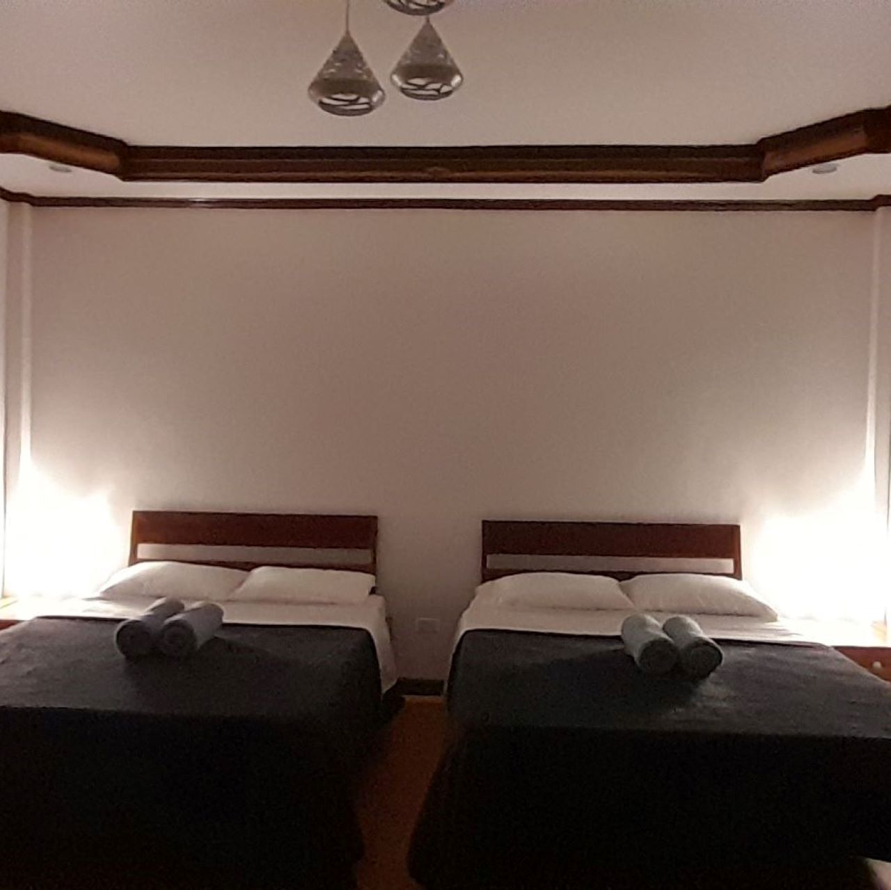 A room with two single beds, wooden headboards, and a simple, clean design.