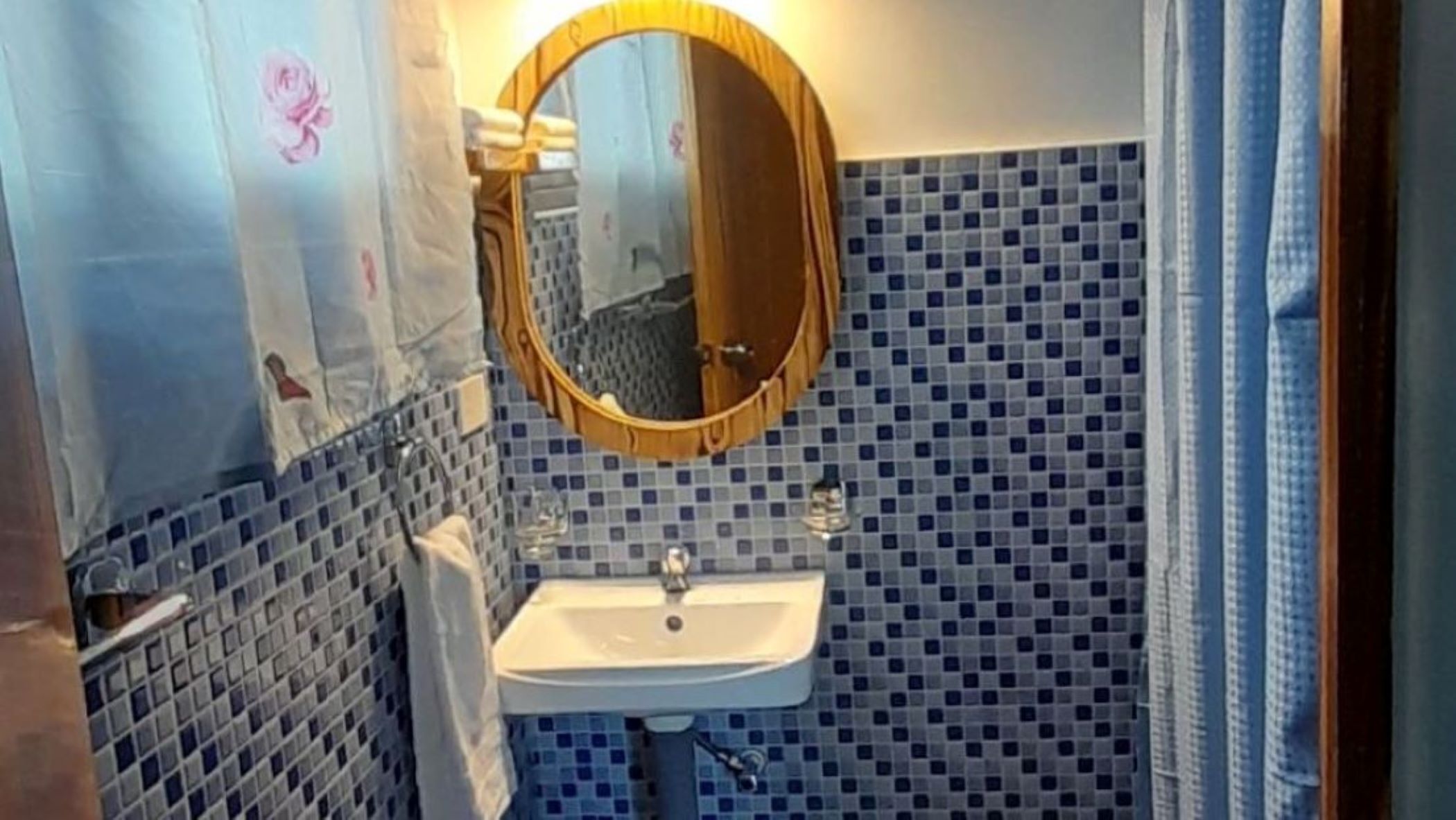 A bathroom with a sink, mirror, and tiled walls.