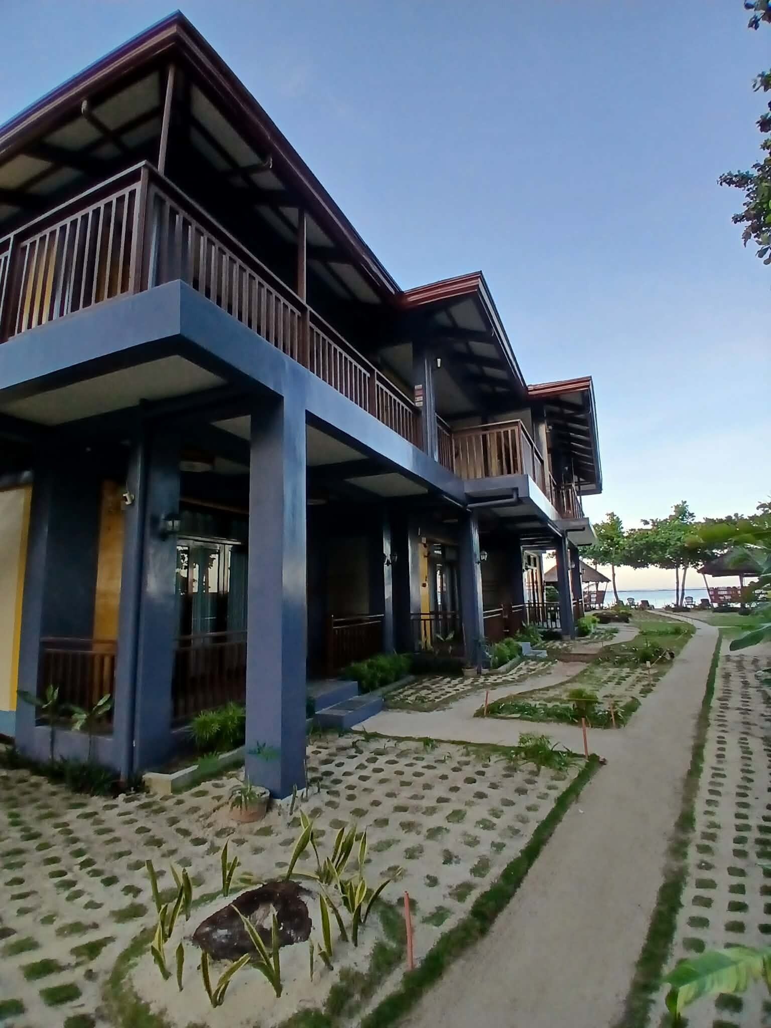 A modern building with multiple balconies, a paved walkway, and a landscaped garden area.