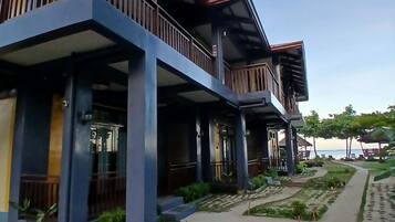 A modern building with multiple balconies, a paved walkway, and a landscaped garden area.