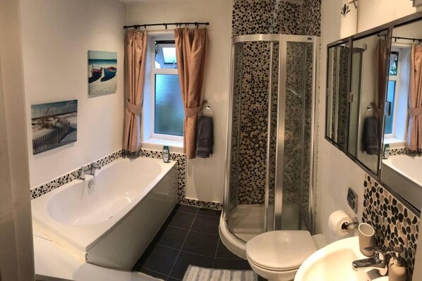 Een aparte badkuip en douche, een diep bad, handdoeken, zeep