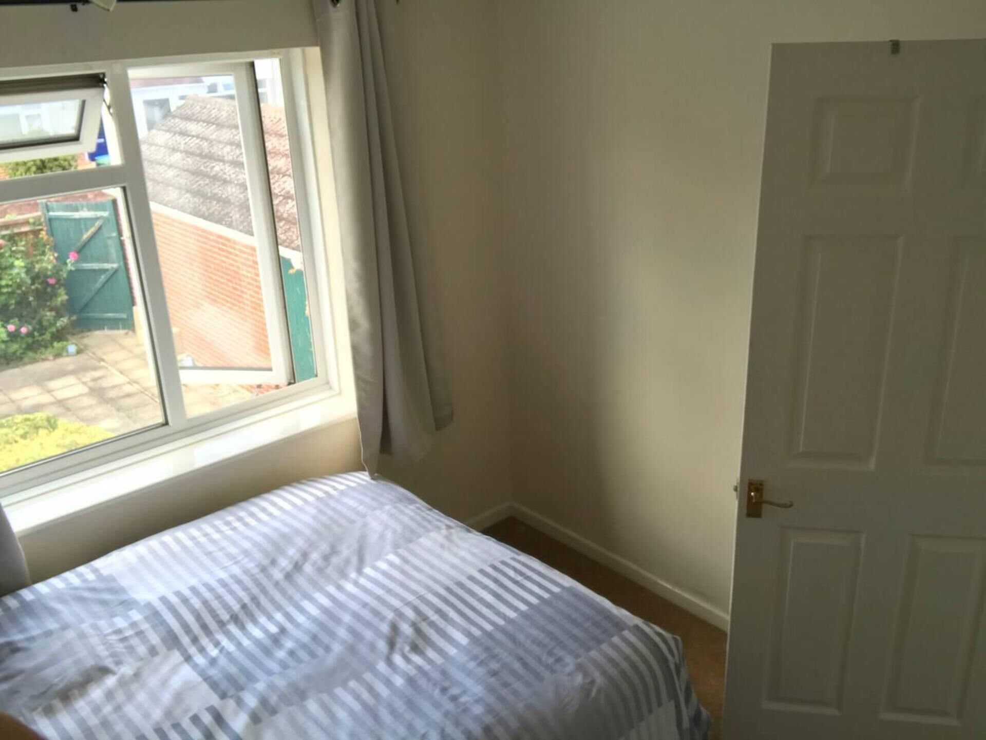 A bedroom with a bed, a window, and a door.