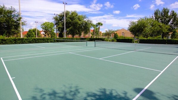 A tennis court with a net, surrounded by trees and buildings. - Amazing 3 Bed Condo in Windsor Hills - Close to Disney! (Kissimmee)