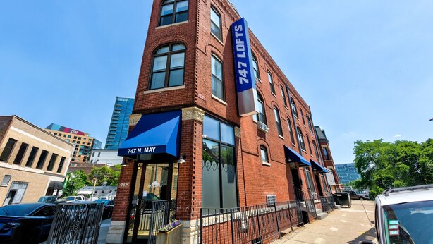 A red brick building with a blue awning and a sign reading "747 LOFTS."