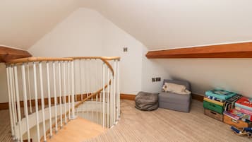 Una habitación con una escalera de madera, un banco acolchado y una colección de juegos de mesa.