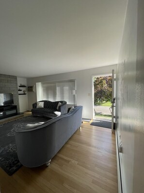 A modern living room with a dark grey sofa, a flat-screen TV, and a fireplace. - Home in Stratford (Stratford)
