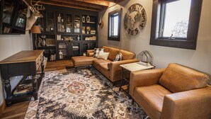 Un salon chaleureux avec un canapé en cuir, une table basse et un tapis à motifs. Le plafond est en bois et il y a une fenêtre avec vue.