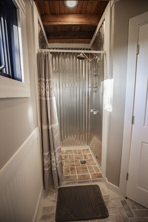 A shower with a shower curtain, a showerhead, and a small window. - The Guesthouse Getaway (Lindsborg)