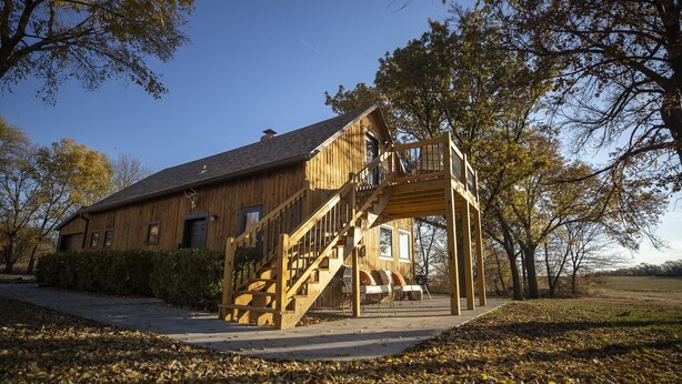 Une cabane en bois avec un escalier en bois menant à une terrasse.