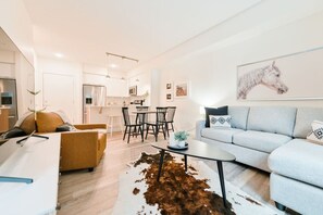 Ein modernes Wohnzimmer mit einer Couch, einem Couchtisch und einem Essbereich mit Stühlen und Tisch.