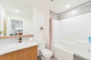 Ein modernes Badezimmer mit Waschbecken, Spiegel, Toilette und Dusche.