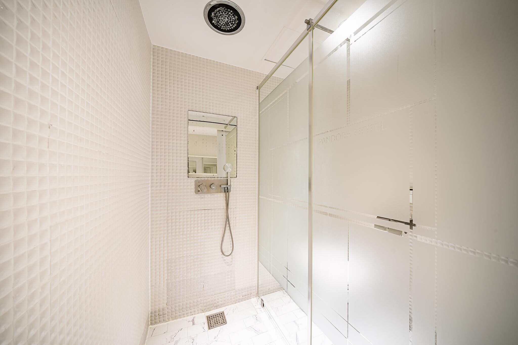 Ein modernes Badezimmer mit Duschabtrennung aus Glas, einem wandmontierten Spiegel und Fliesenboden.
