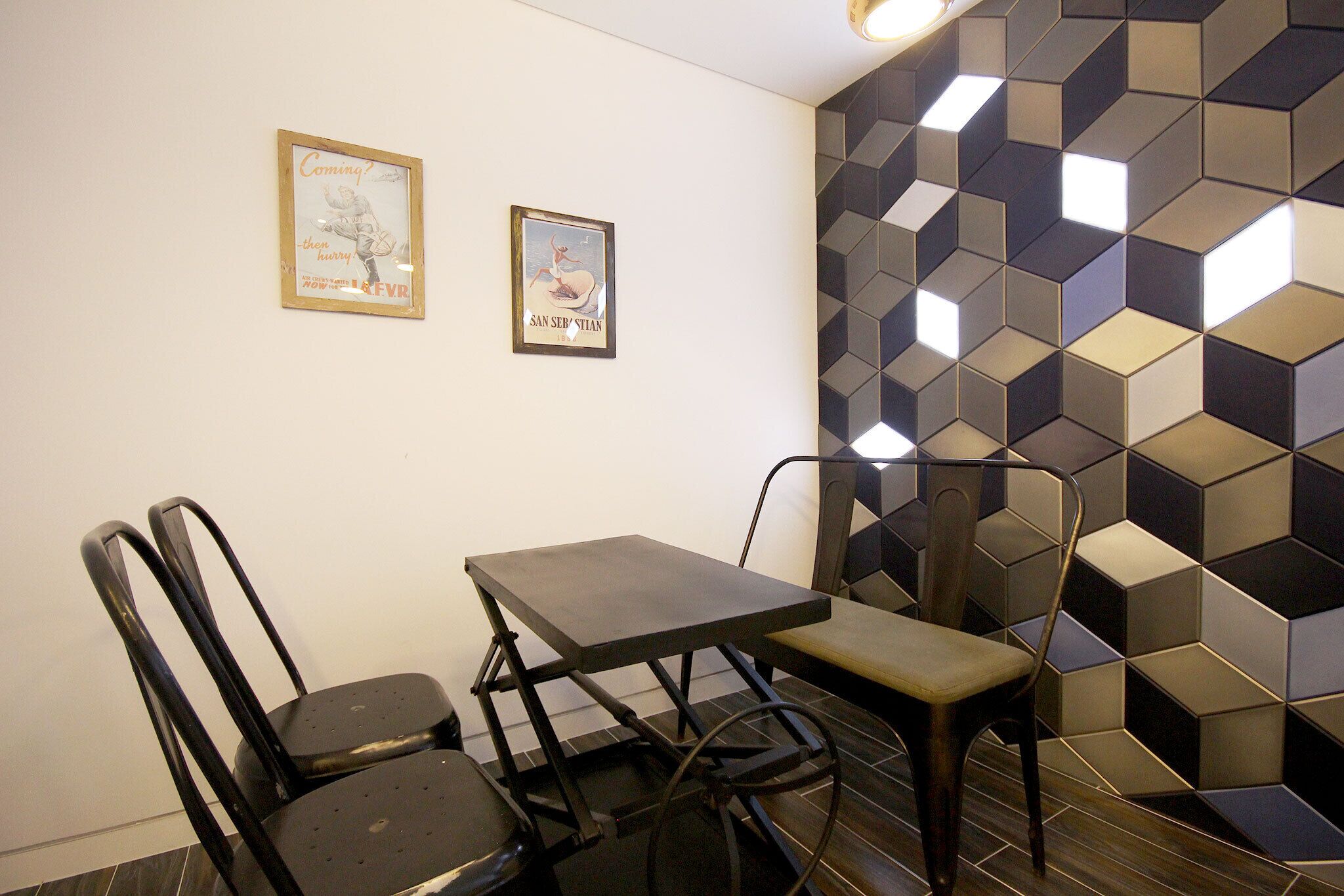 A dining area with a table and chairs, two framed pictures on the wall, and a geometric patterned wall.