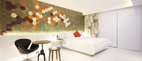 A modern bedroom with a large bed, a black chair, a small round table, and a hexagonal wall art piece.