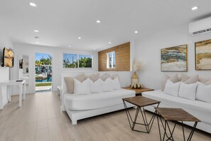 A modern living room with a white sofa, a wooden coffee table, and a view of a pool. - 1. Key Largo Waterfront Studio | Canal & Ocean (Key Largo)