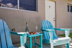 A two-chair outdoor seating area with a table, a bottle, and a glass.