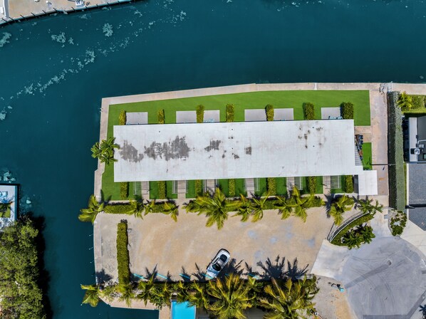 An aerial view of a waterfront property with a long building, a parking area, and a beach.