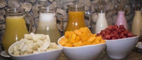 Un bufé de desayuno con diversas frutas y bebidas.