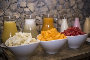 Un bufé de desayuno con diversas frutas y bebidas.