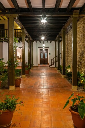 A corridor with tiled flooring, wooden columns, and potted plants. - La Xalca Hotel - Hotel Asociado Casa Andina (Chachapoyas)