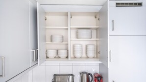 Una cocina con armarios blancos, horno empotrado, tostadora, hervidor y cafetera.