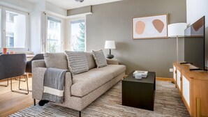 Una sala de estar moderna con un sofá, una mesa de centro, un televisor y una lámpara.