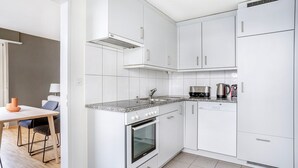 Una cocina moderna con armarios blancos, encimera de granito y electrodomésticos de acero inoxidable.