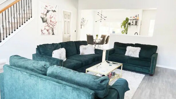 Ein Wohnzimmer mit türkisfarbenen Sofas, einem Couchtisch und einer Treppe.
