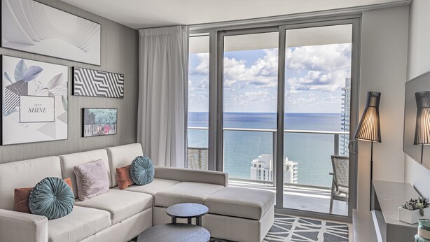 A modern living room with a large window, a sofa, a small round table, and artwork on the wall. - <br>★★★★★ Hyde Hotel Condo 2BD/2BA Amazing view and excellent RESSORT (Hollywood)